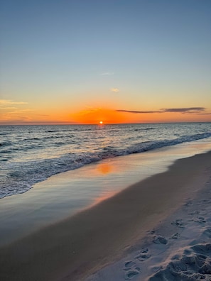 Una playa con un atardecer sobre el océano.