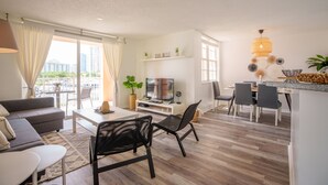 A modern living room with a sofa, dining table, chairs, and a TV.