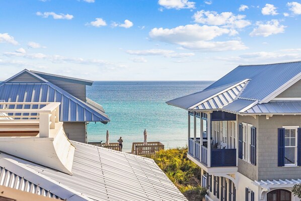 A coastal building with a view of the sea, featuring a balcony and a covered outdoor area. - Providence Cottage in Rosemary Beach, 3rd tier home from Gulf with Gulf view (Rosemary Beach)