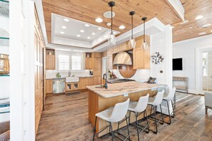 A modern kitchen with wooden cabinets, a central island with bar stools, and pendant lighting. - Providence Cottage in Rosemary Beach, 3rd tier home from Gulf with Gulf view (Rosemary Beach)