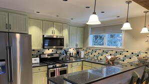 Una cocina moderna con electrodomésticos de acero inoxidable, una isla grande con taburetes de bar y un ventanal que proporciona luz natural.