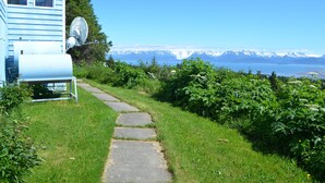 A stone pathway leading to a house with a satellite dish and a water tank. - Miracle Ridge - Beautiful, Private Home Overlooking Kachemak Bay & Cook Inlet (Homer)