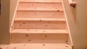 Una escalera de madera con barandilla, que conduce a una plataforma.
