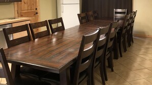 Un comedor con una mesa y sillas de madera, un refrigerador blanco y una puerta de madera.