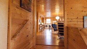 A wooden interior with a staircase leading to a laundry area, a chair, and a table with a lamp. - Fantastic House In Grand Marais! Walking Distance To Downtown! (Grand Marais)