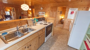 A kitchen with wooden cabinets, a stove, a sink, and a refrigerator. - Fantastic House In Grand Marais! Walking Distance To Downtown! (Grand Marais)