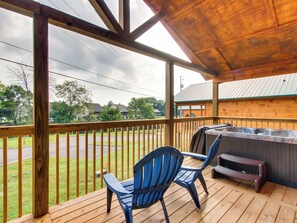 A covered deck with wooden railings, two blue chairs, and a barbecue grill.
