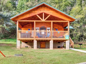 A wooden cabin with a porch, stone foundation, and a sign indicating 'Aunt Bug's'.