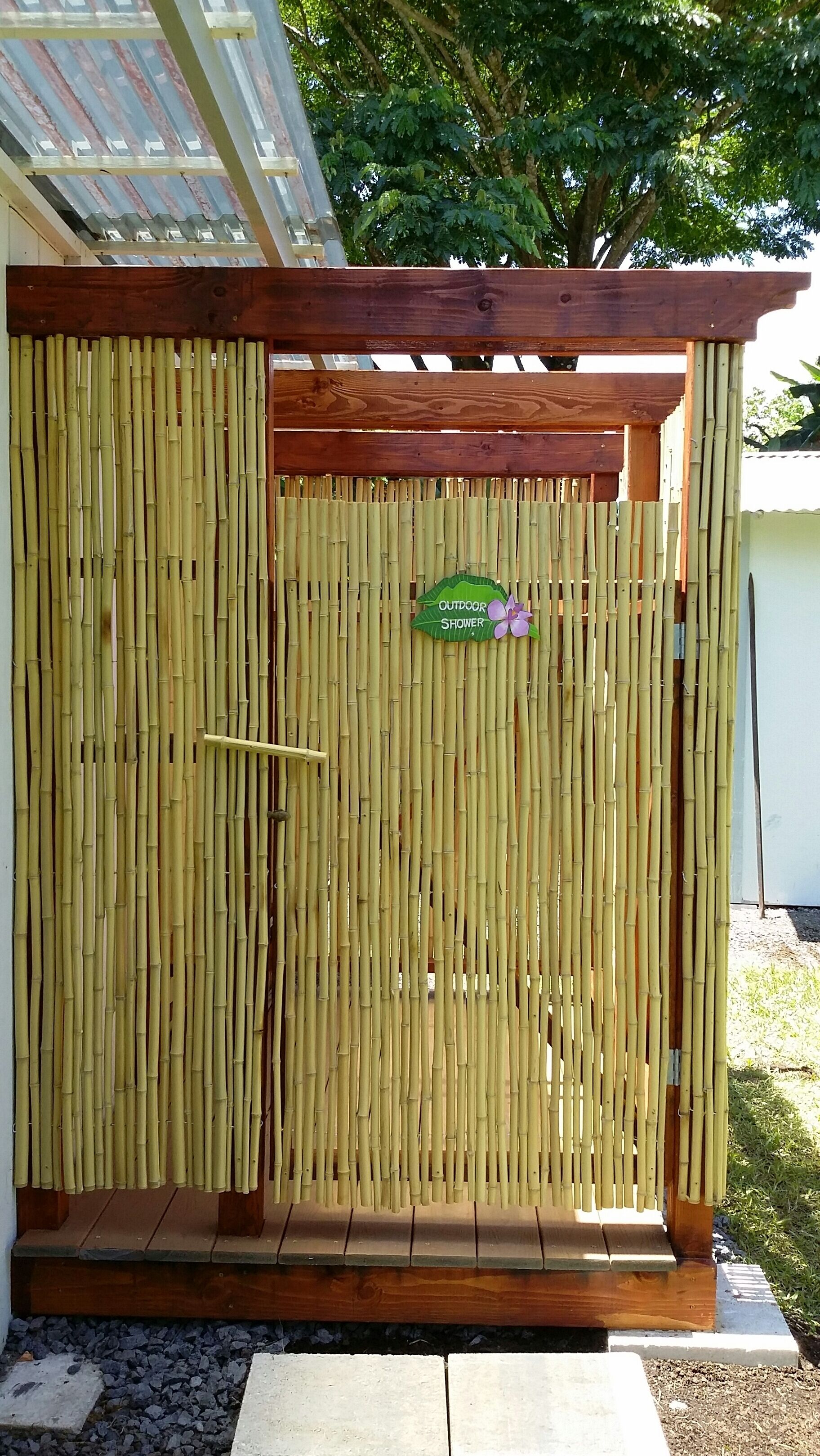 A bamboo fence with a sign that reads "OUTDOOR SHOWER".