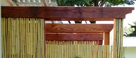 A bamboo fence with a sign that reads "OUTDOOR SHOWER".