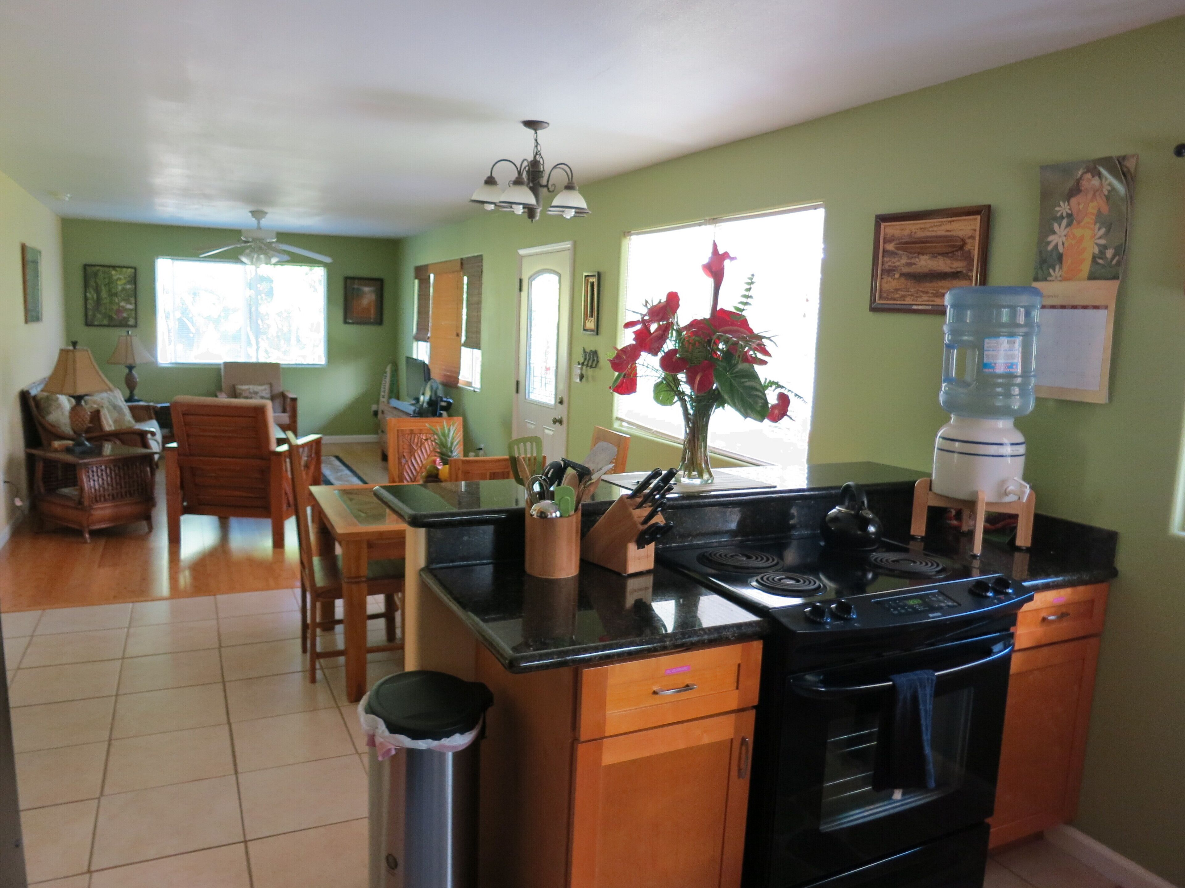 A kitchen with a stove, sink, and dining area with chairs and a table.