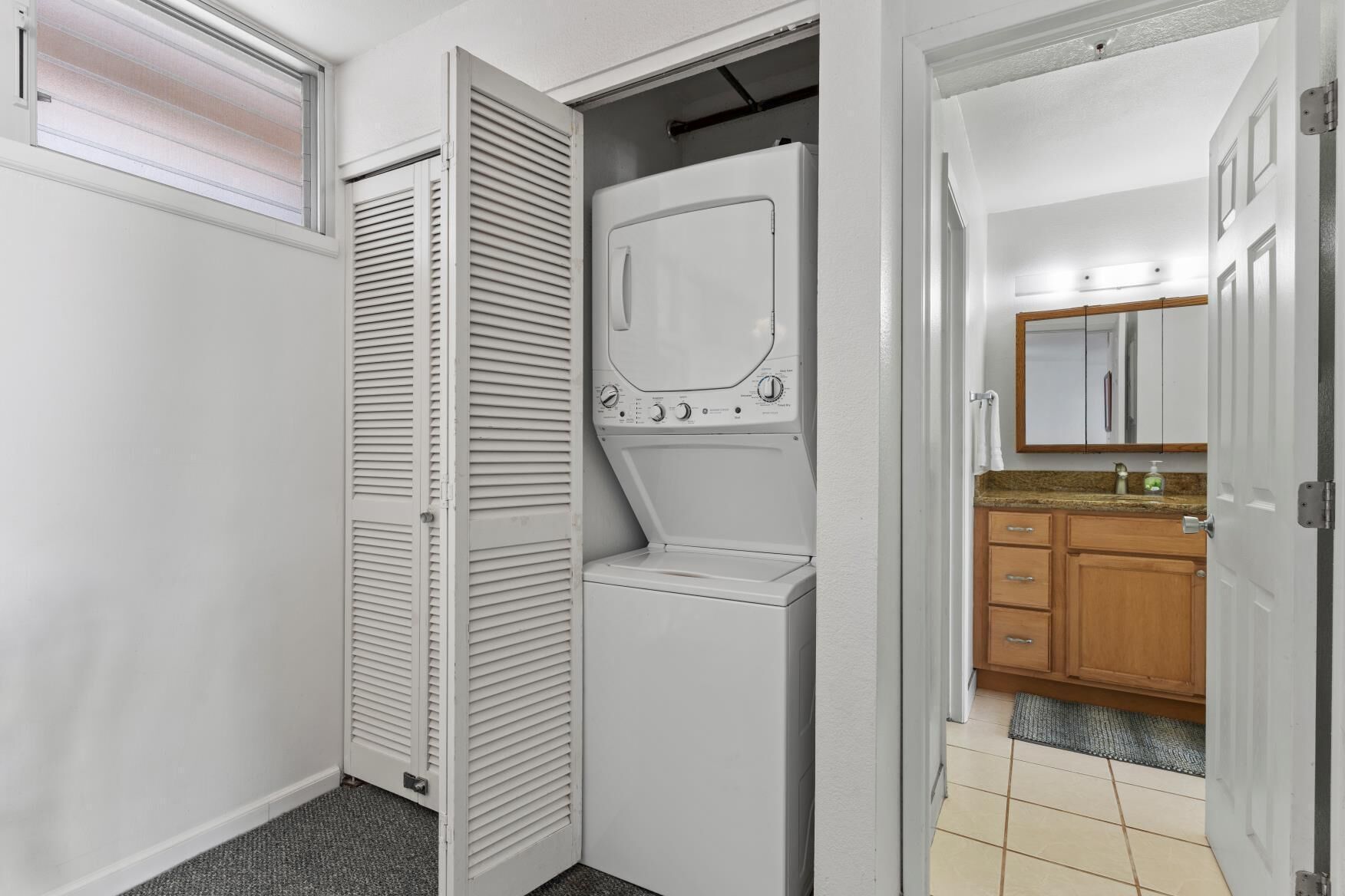 Een kleine kamer met een wasmachine, een spiegel en een houten kast.