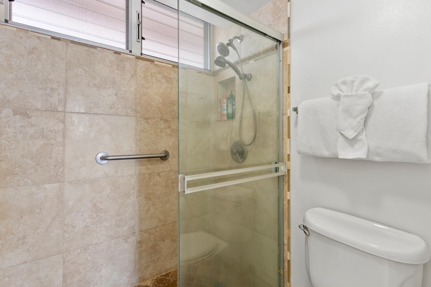 Une salle de bain moderne avec une douche à parois de verre, des toilettes et un porte-serviettes.