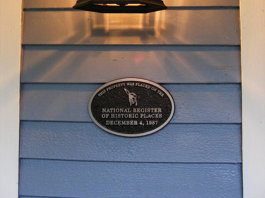 Een verlichte lantaarn op een gevel, met een plaquette eronder die vermeldt dat het een monument is dat op de Nationale Registerlijst staat.
