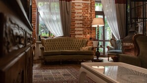 A cozy living room with a green sofa, a patterned rug, and a brick wall. - Good Time Aparthotel (Lodz)