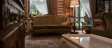 A cozy living room with a green sofa, a patterned rug, and a brick wall.