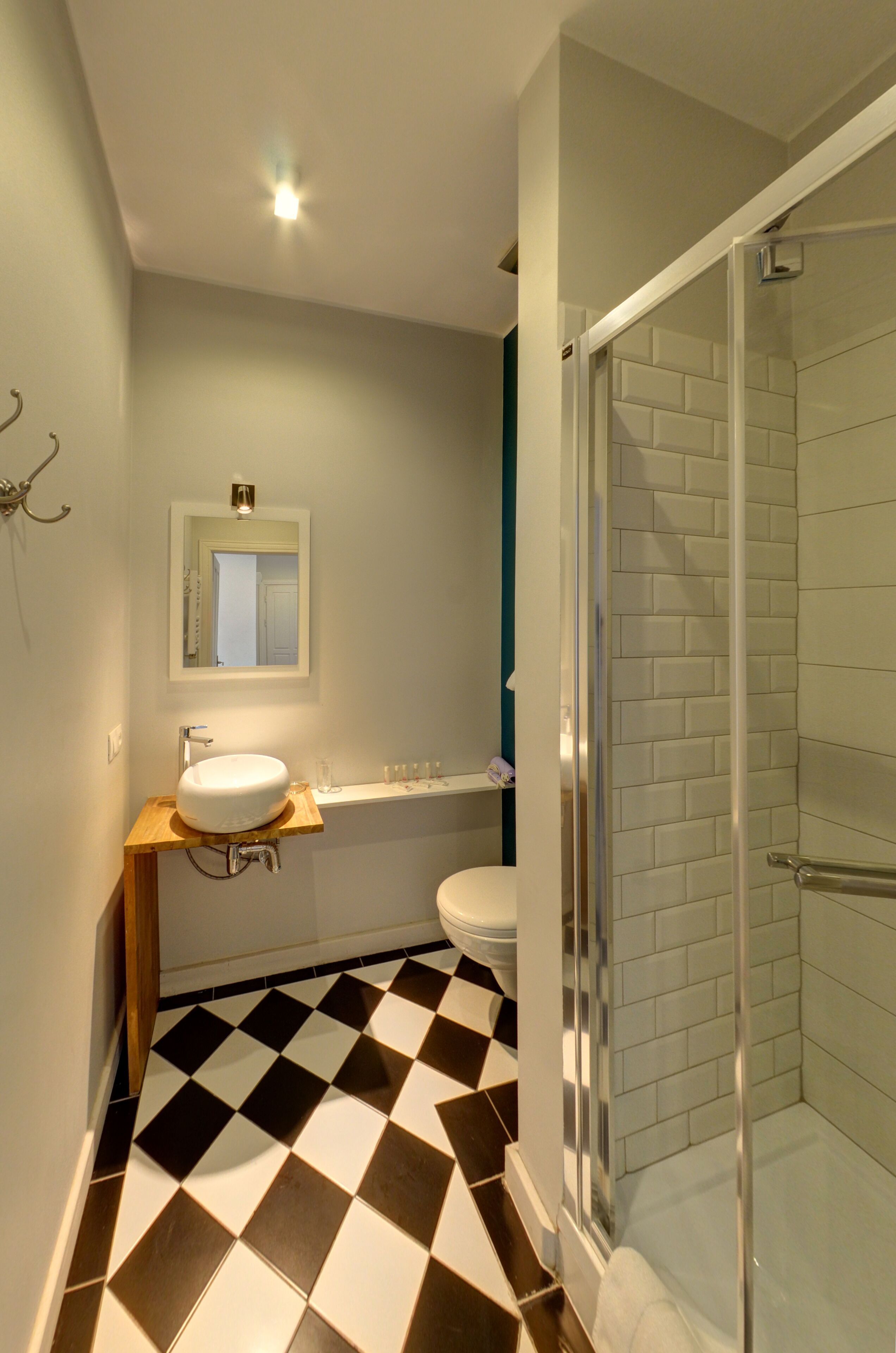 A bathroom with a checkered floor, a white sink, a mirror, and a glass-enclosed shower.