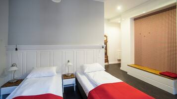 Ein Hotelzimmer mit zwei Betten, einer hölzernen Bank, einer Wand mit Muster und einer Uhr.