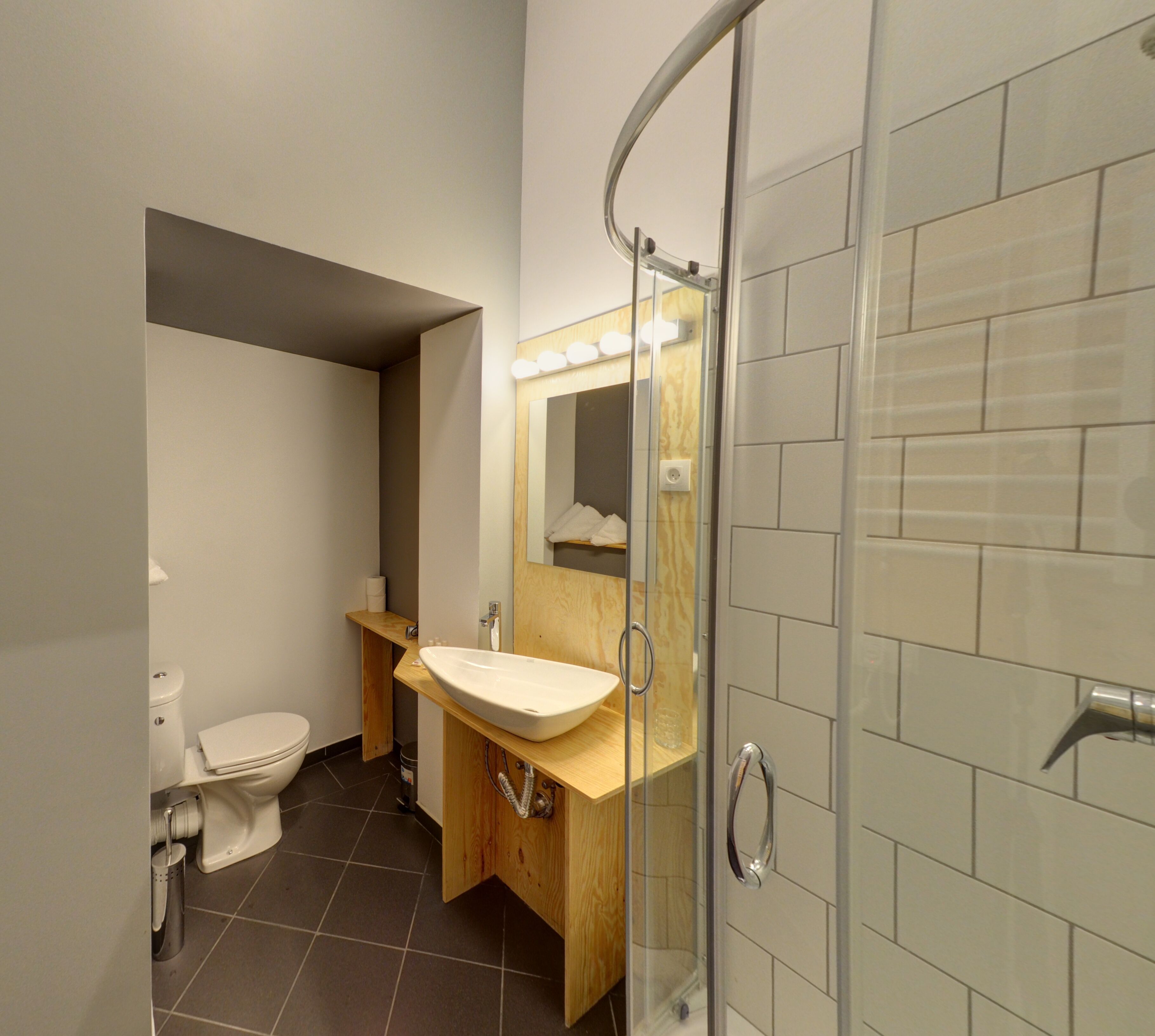 A modern bathroom with a glass shower enclosure, a wooden vanity, and a white toilet.