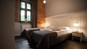 A bedroom with two beds, a brick wall, a window, and a white headboard. - Good Time Aparthotel (Lodz)