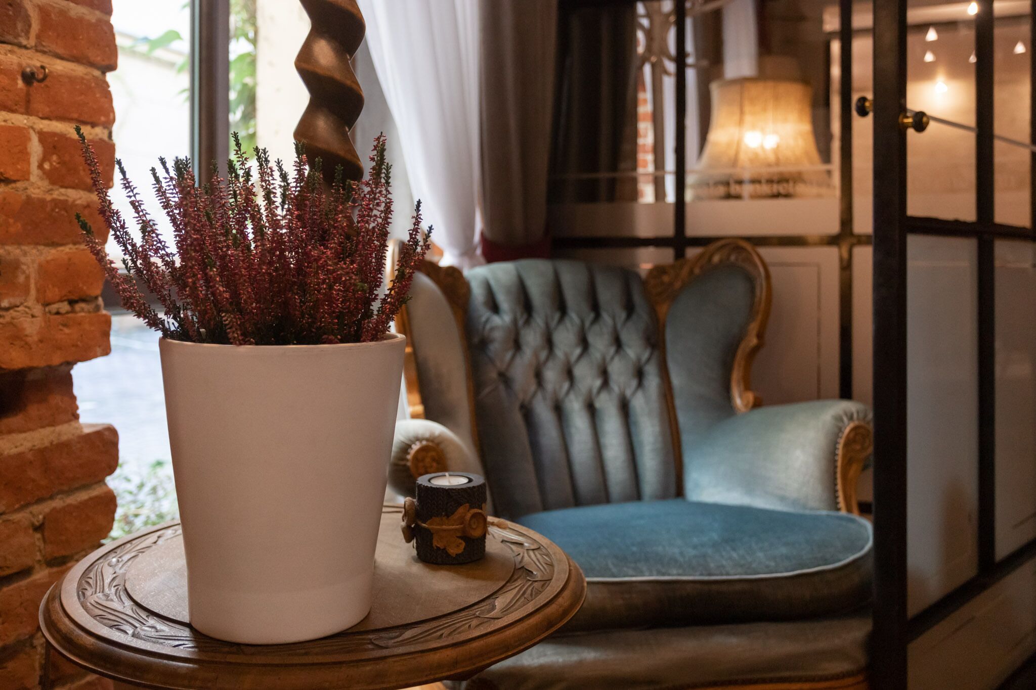 A cozy room with a potted plant, a blue upholstered chair, and a lamp.