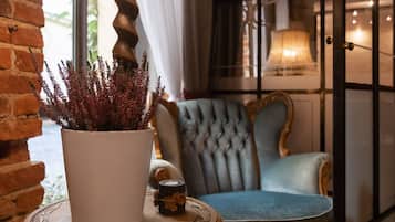 A cozy room with a potted plant, a blue upholstered chair, and a lamp.
