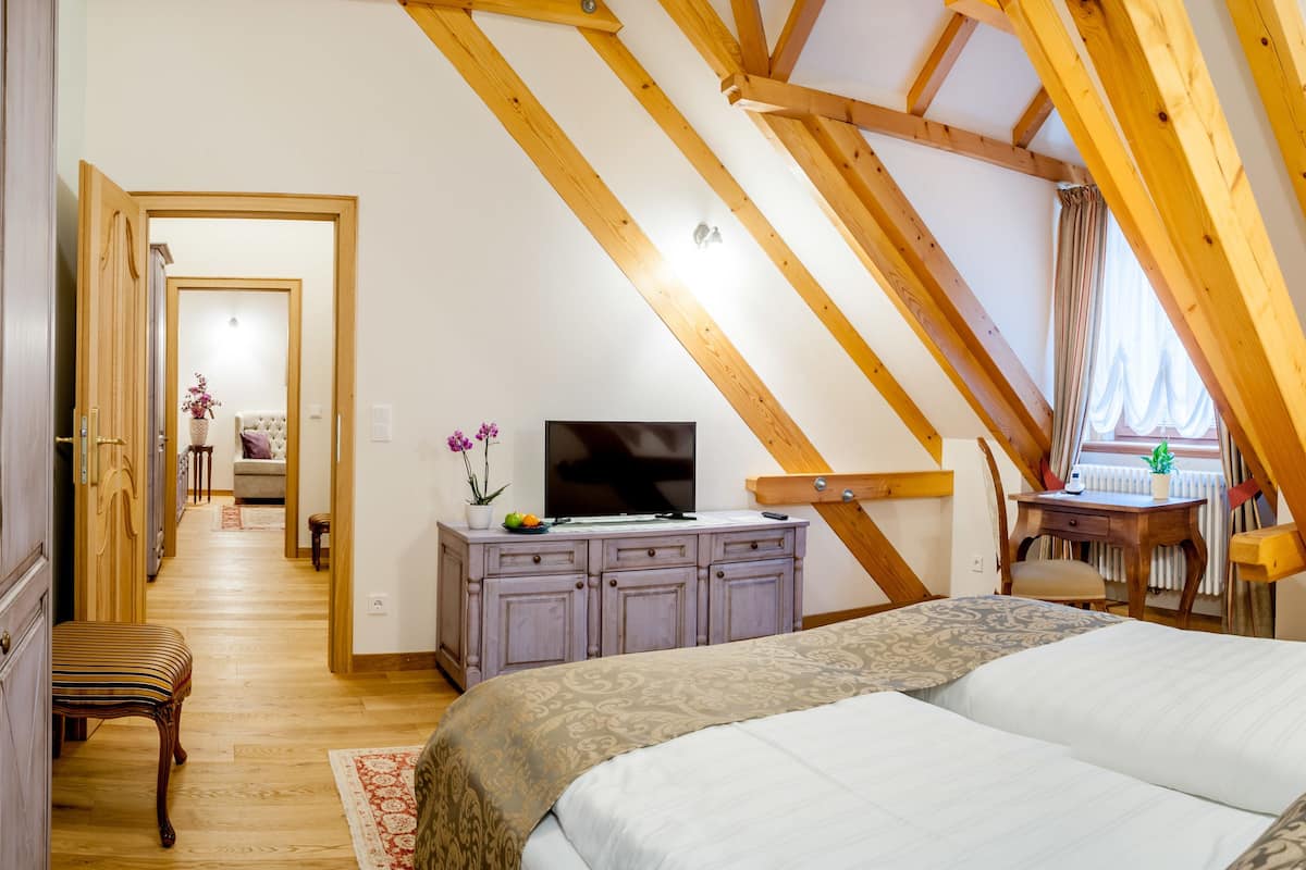 Une chambre avec un plafond en pente, un lit, un bureau et une chaise.