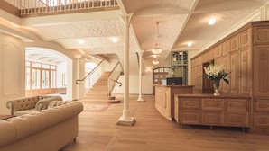 Un espacio habitable espacioso con techo alto, piso de madera, una escalera y un sofá grande color beige.