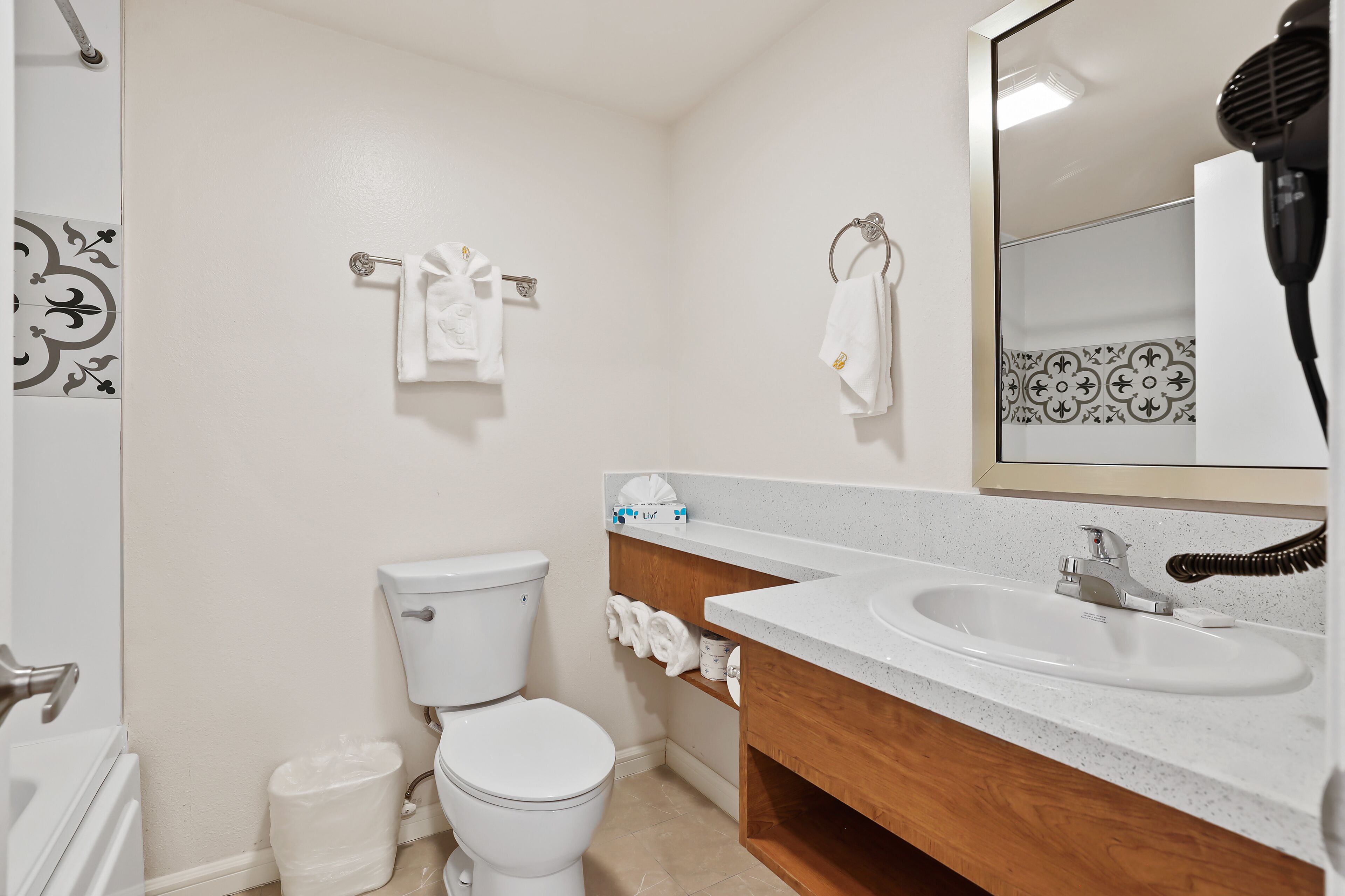 A bathroom with a white toilet, a sink with a mirror, and a towel rack with towels.