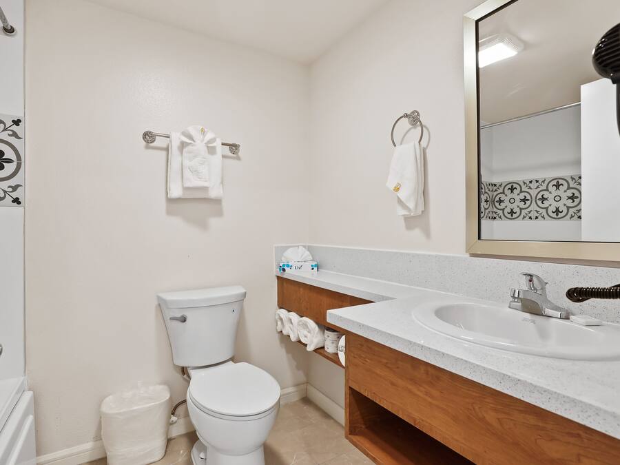 A bathroom with a white toilet, a sink with a mirror, and a towel rack with towels.