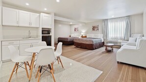 A modern, well-lit room with a kitchenette, a dining area, and a bed. - Brookhurst Plaza Inn (Anaheim)