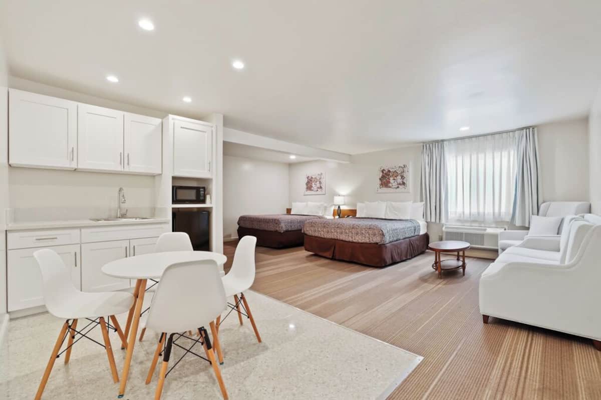 Una habitación moderna y bien iluminada con kitchenette, zona de comedor y cama.