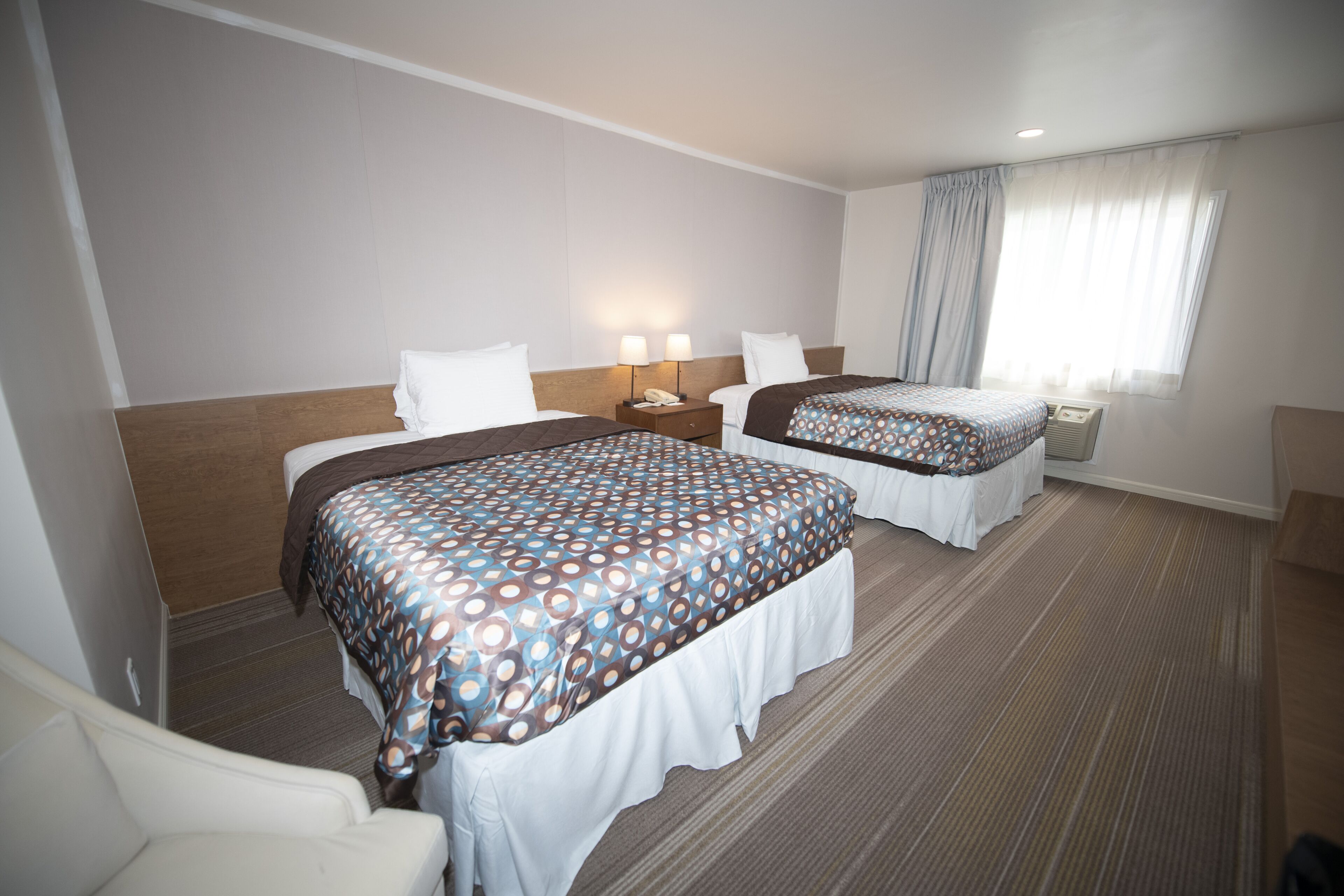 Ett hotellrum med två sängar, ett skrivbord och en stol.