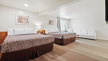 A hotel room with two beds, a sofa, and artwork on the walls.