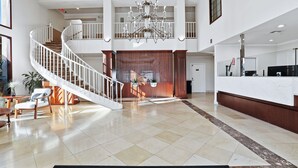 A spacious lobby with a grand staircase, a chandelier, and a reception desk. - Brookhurst Plaza Inn (Anaheim)