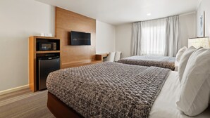 A hotel room with two beds, a TV, a minibar, and a window with curtains. - Brookhurst Plaza Inn (Anaheim)