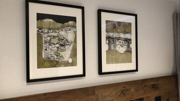 Two framed artworks on a wall with a wooden headboard below.