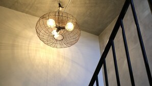 Uma escadaria com corrimão de metal preto e um lustre com três lâmpadas.