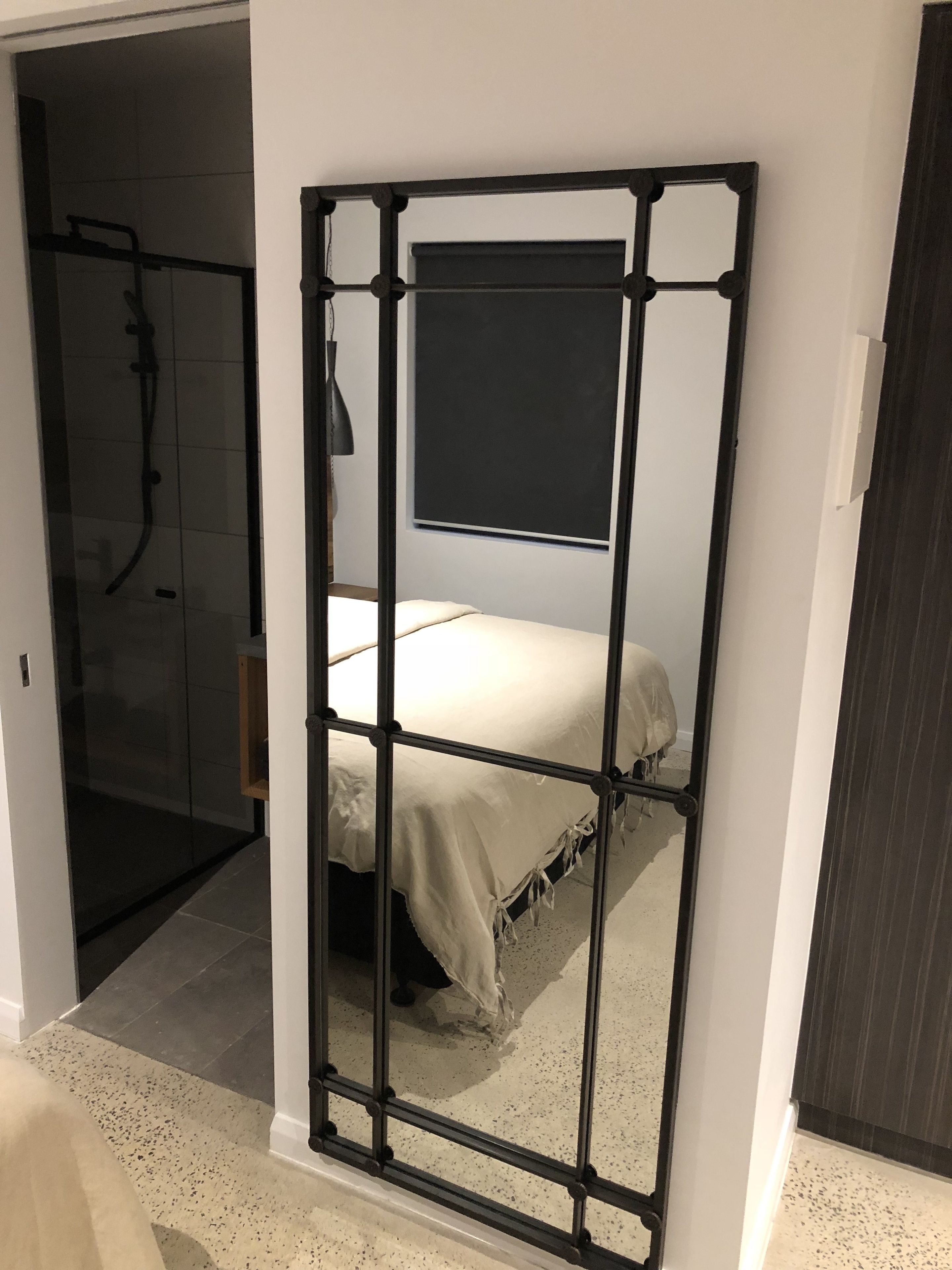 Una habitación con cama, ducha y un espejo grande.
