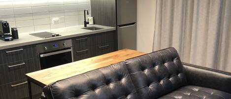 Una cocina moderna con armarios oscuros, una mesa de comedor de madera y un sofá de cuero negro.