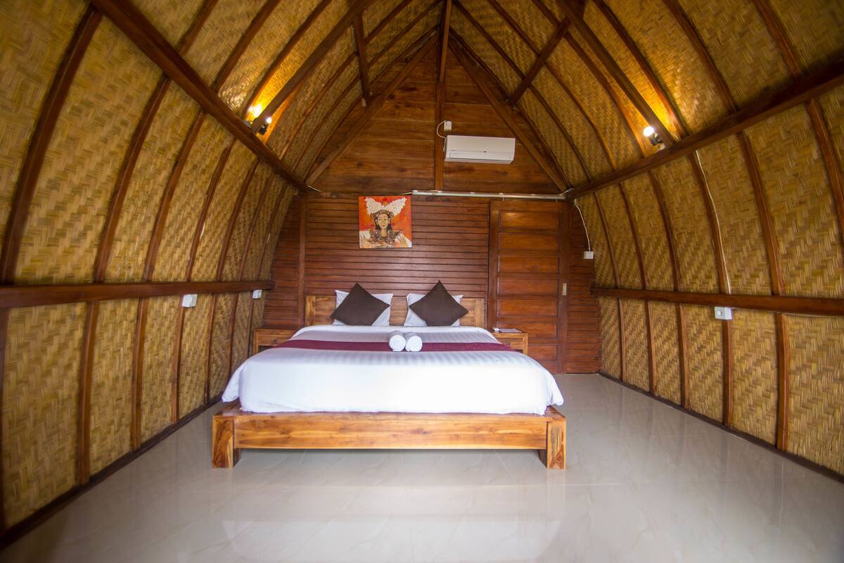A room with a wooden ceiling and walls, a bed with pillows, and a painting on the wall.