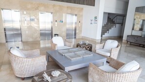 A lobby with wicker furniture, a central coffee table, and a staircase in the background. - Luxury apartment facing the sea (Cartagena)