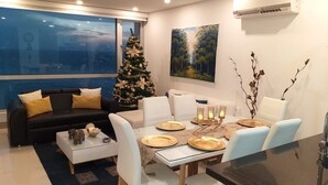 A modern living room with a dining area, a Christmas tree, and a painting on the wall. - Luxury apartment facing the sea (Cartagena)