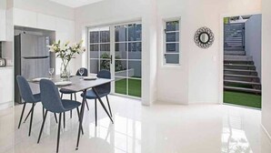Eine moderne Küche mit weißen Schränken, einem Edelstahl-Kühlschrank und einem Essbereich mit Tisch und Stühlen.