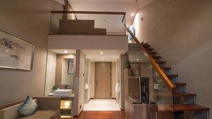Un interior moderno con una escalera, un sofá, un televisor y un baño con un lavamanos.