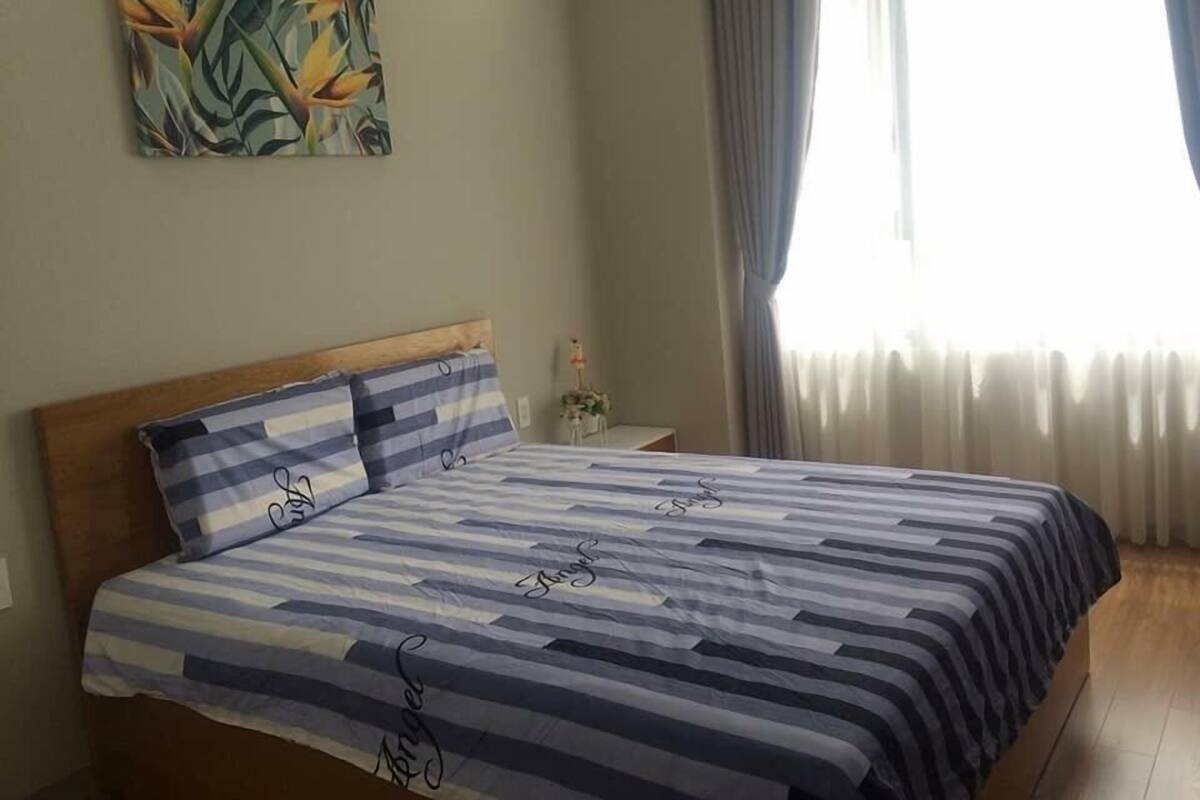 A bedroom with a bed, a nightstand, a lamp, and a painting on the wall.
