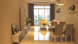 A modern living room with a sofa, coffee table, and dining area. - Hung Phat 2 Silver Star Apartment Room TNT (Ho Chi Minh City)
