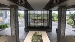 A modern building entrance with a central planter, large pillars, and a metal fence with a festive message. - Hung Phat 2 Silver Star Apartment Room TNT (Ho Chi Minh City)