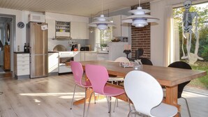 A modern kitchen with a wooden dining table, pink and white chairs, and pendant lights. - Nice home in Esbjerg V with WiFi (Esbjerg V)