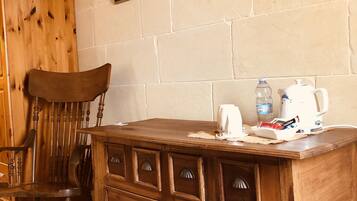 A wooden desk with drawers, a chair, a framed picture on the wall, and a tiled floor.